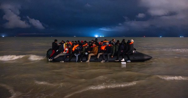 TOPSHOT - Migrants board a smuggler's inflatable dinghy in an attempt to cross the English Channel, on Bleriot beach in Sangatte, near Calais, northern France on October 30, 2024. (Photo by Sameer Al-DOUMY / AFP)