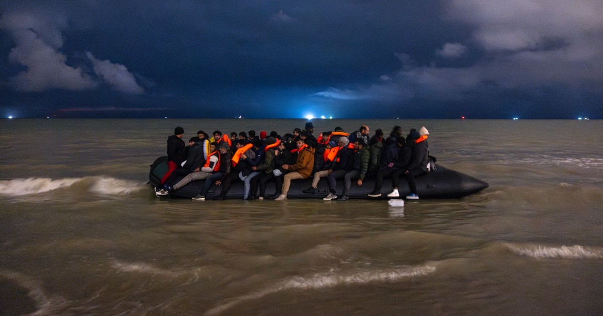 TOPSHOT - Migrants board a smuggler's inflatable dinghy in an attempt to cross the English Channel, on Bleriot beach in Sangatte, near Calais, northern France on October 30, 2024. (Photo by Sameer Al-DOUMY / AFP)